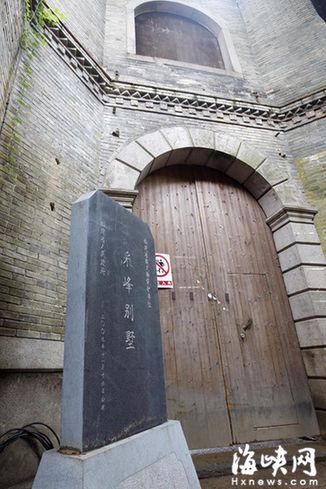 采峰別墅前的黑色大理石石碑，和后面的磚石建筑及木門，很不搭