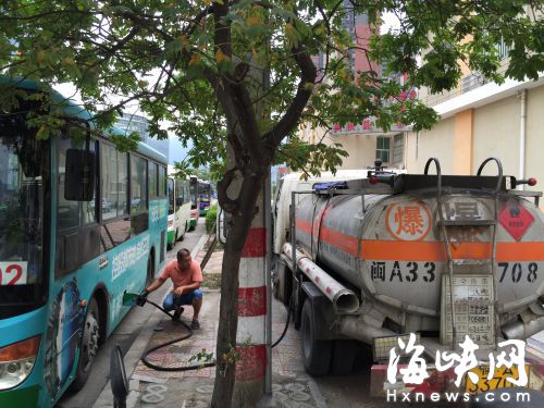 油罐車正在給停在路邊的公交車加油